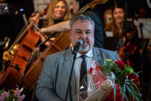 Zdjęcie przedstawia dyrektora CKiS Piotra Pułkowskiego z orkiestrą w tle.